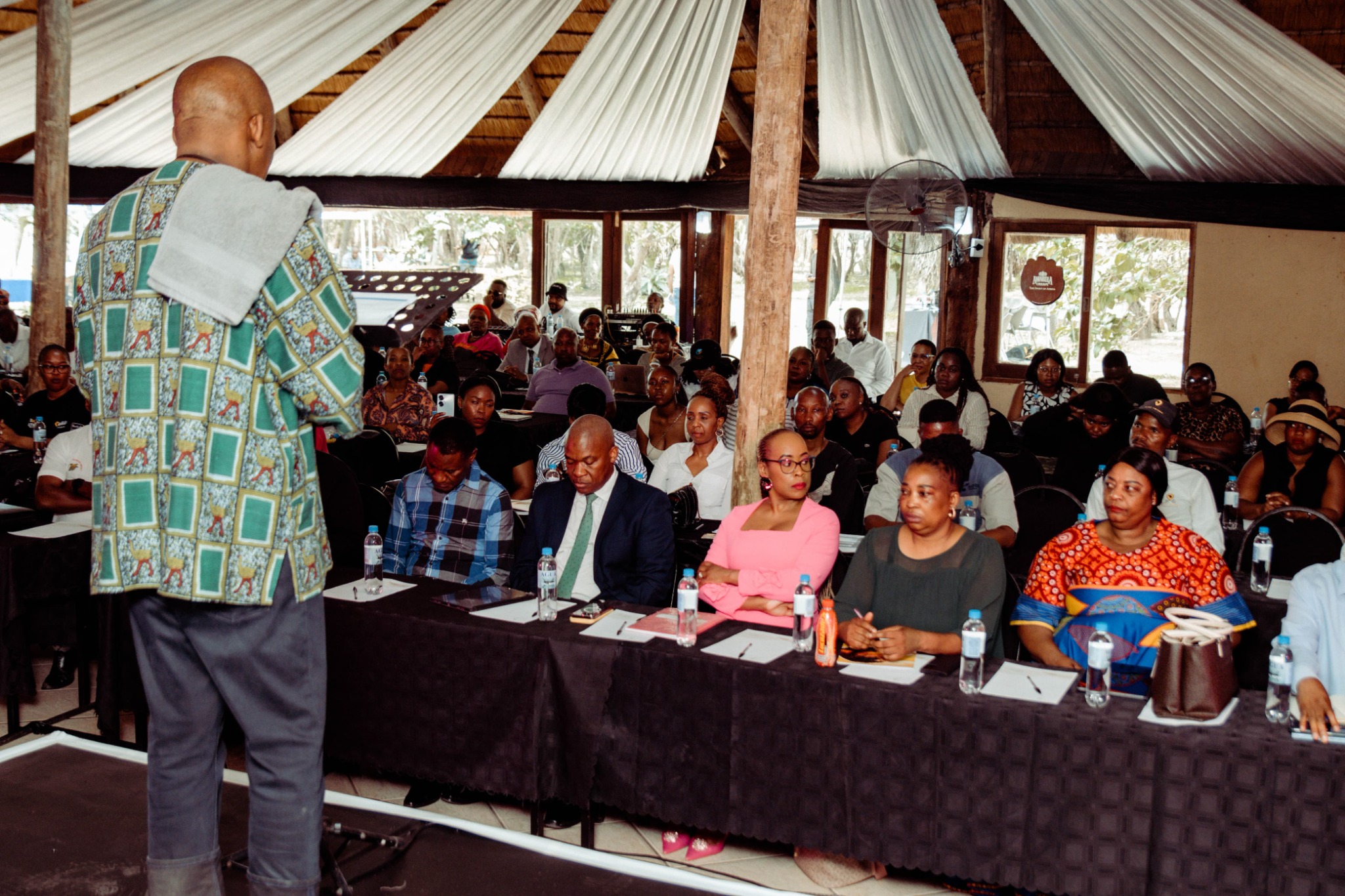 A speaker addressing seated delegates at a SATOVITO gathering